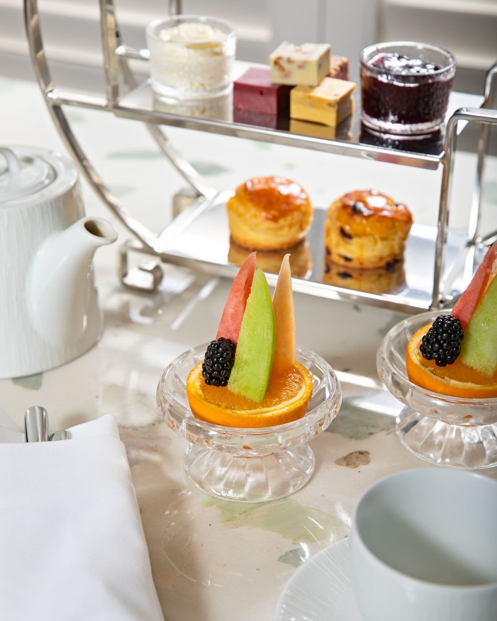Tiered afternoon tea stand with pastries, scones and fruit